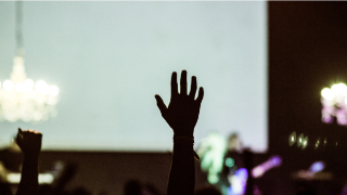 A rised hand at a group learning seminar held at One&Co